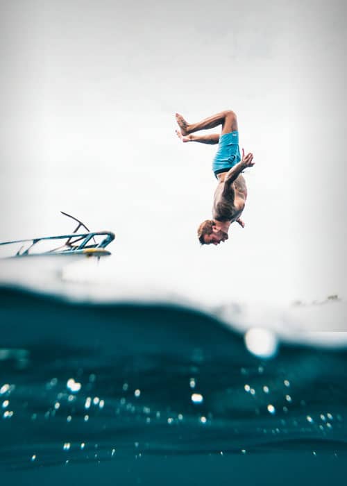 Person backflipping off boat into turquoise water